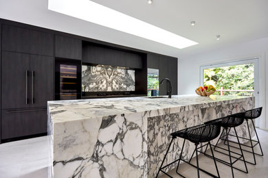 Inspiration for a large modern galley kitchen pantry in Sunshine Coast with an integrated sink, flat-panel cabinets, black cabinets, marble benchtops, white splashback, marble splashback, black appliances, porcelain floors, with island, beige floor and white benchtop.