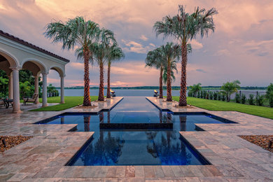Design ideas for a large modern backyard custom-shaped infinity pool in Tampa with a hot tub and natural stone pavers.