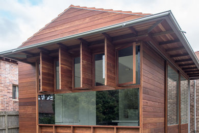 Imagen de fachada de casa marrón y roja contemporánea de tamaño medio de una planta con revestimiento de madera y tejado de teja de barro