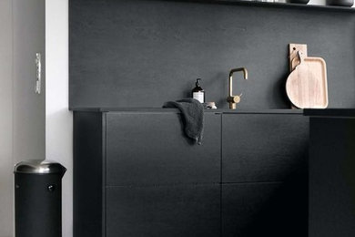Foto på ett mellanstort minimalistiskt turkos kök, med en enkel diskho, släta luckor, svarta skåp, bänkskiva i kvarts, svart stänkskydd, stänkskydd i trä, vita vitvaror, ljust trägolv, en halv köksö och beiget golv