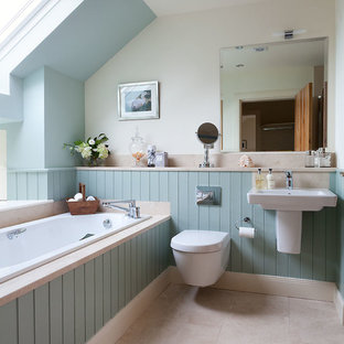 Idée de décoration pour une salle de bain marine avec un WC à poser, un mur bleu, un sol en calcaire, un lavabo suspendu et un plan de toilette en calcaire.