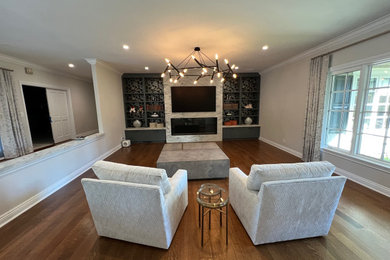 Mid-sized open concept medium tone wood floor and brown floor family room photo in San Francisco with beige walls, a standard fireplace, a stone fireplace and a media wall