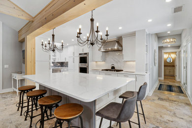 Example of a mid-sized beach style galley ceramic tile, beige floor and vaulted ceiling open concept kitchen design in Other with an undermount sink, shaker cabinets, white cabinets, granite countertops, white backsplash, granite backsplash, stainless steel appliances, an island and white countertops