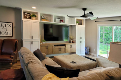 Modelo de sala de estar clásica renovada de tamaño medio con paredes beige, suelo vinílico, televisor colgado en la pared y suelo marrón