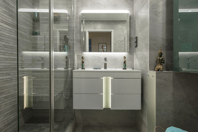 Photo of a small contemporary master bathroom in Paris with a curbless shower, gray tile, grey walls, a wall-mount sink, grey floor, white benchtops, white cabinets, a hinged shower door and porcelain floors.