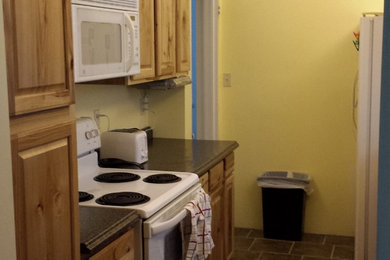 Enclosed kitchen - small traditional galley ceramic tile enclosed kitchen idea in Kansas City with a double-bowl sink, raised-panel cabinets, light wood cabinets, white appliances and no island