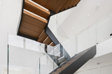 Ejemplo de escalera suspendida minimalista de tamaño medio con escalones de madera, contrahuellas de madera y barandilla de vidrio