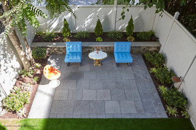 Photo of a small mid-century modern shade backyard concrete paver retaining wall landscape in New York for winter.