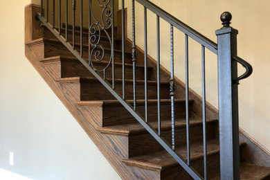 Ejemplo de escalera recta clásica de tamaño medio con barandilla de metal, escalones de madera y contrahuellas de madera