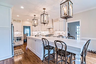 Mid-sized transitional u-shaped medium tone wood floor and brown floor eat-in kitchen photo in Nashville with a farmhouse sink, shaker cabinets, white cabinets, quartz countertops, multicolored backsplash, mosaic tile backsplash, stainless steel appliances, an island and white countertops