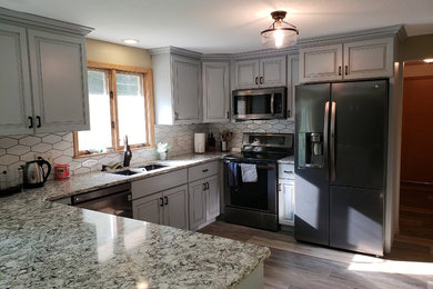 Eat-in kitchen - mid-sized transitional u-shaped medium tone wood floor and brown floor eat-in kitchen idea in Other with an undermount sink, raised-panel cabinets, gray cabinets, granite countertops, white backsplash, ceramic backsplash, stainless steel appliances, a peninsula and multicolored countertops