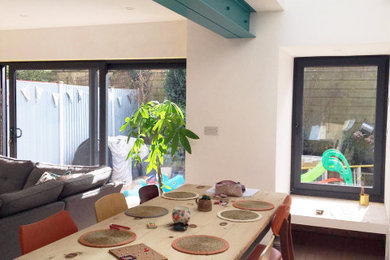 Photo of a medium sized contemporary kitchen/dining room in Kent with laminate floors and exposed beams.