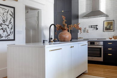 Eat-in kitchen - mid-sized l-shaped light wood floor eat-in kitchen idea in Vancouver with white backsplash, paneled appliances, an island, white countertops and an undermount sink