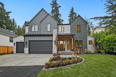 Example of a large farmhouse gray two-story board and batten and wood exterior home design in Seattle with a black roof and a metal roof