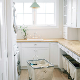Traditional u-shaped separated utility room in Boston with a built-in sink, shaker cabinets, white cabinets, white walls, a stacked washer and dryer and beige worktops.