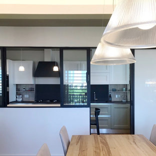 Design ideas for a large contemporary u-shaped eat-in kitchen in Rome with an undermount sink, raised-panel cabinets, white cabinets, solid surface benchtops, black splashback, slate splashback, stainless steel appliances, porcelain floors, brown floor and black benchtop.