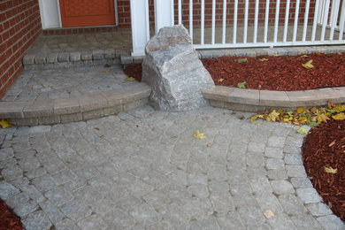 Small concrete paver front porch idea in Ottawa with a roof extension