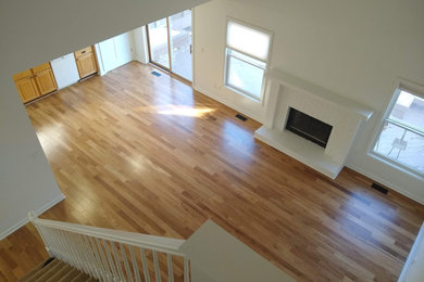 Huge trendy open concept light wood floor and brown floor family room photo in Detroit with white walls, a standard fireplace and a brick fireplace