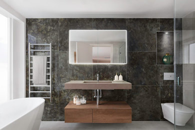 Inspiration for a medium sized modern ensuite wet room bathroom in London with flat-panel cabinets, medium wood cabinets, a freestanding bath, a wall mounted toilet, multi-coloured tiles, porcelain tiles, ceramic flooring, an integrated sink, solid surface worktops, beige floors, an open shower, brown worktops, a wall niche, a single sink and a floating vanity unit.