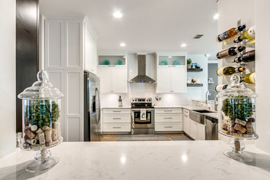 Photo of a mid-sized transitional u-shaped open plan kitchen in Orlando with shaker cabinets, white cabinets, marble benchtops, white splashback, stainless steel appliances, porcelain floors, brown floor, a farmhouse sink and a peninsula.