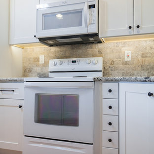 Новый формат декора квартиры: маленькая п-образная кухня-гостиная в стиле современная классика с врезной раковиной, фасадами в стиле шейкер, белыми фасадами, столешницей из гранита, бежевым фартуком, фартуком из травертина, белой техникой, полом из керамической плитки, островом и бежевым полом