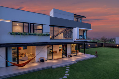 Example of a large minimalist gray three-story concrete exterior home design in Other with a shingle roof