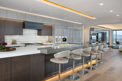 Example of a large trendy galley light wood floor and brown floor kitchen design in Denver with an undermount sink, flat-panel cabinets, dark wood cabinets, quartz countertops, white backsplash, marble backsplash, white appliances, an island and white countertops