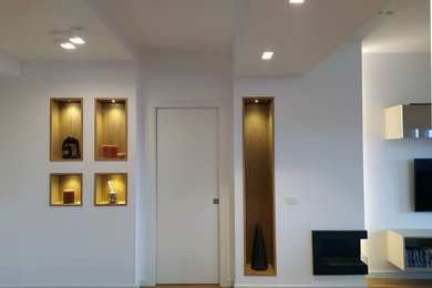 This is an example of a large modern foyer in Rome with white walls, light hardwood floors, a single front door, a white front door, brown floor and recessed.