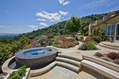 Inspiration for a mid-sized mediterranean backyard custom-shaped infinity pool in San Francisco with a hot tub and natural stone pavers.