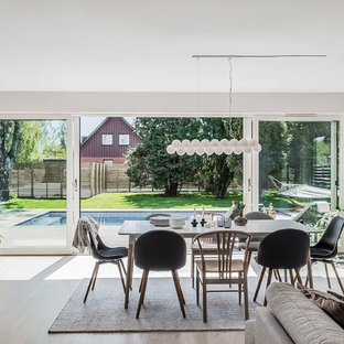 Nordisk inredning av en matplats med öppen planlösning, med grå väggar, ljust trägolv, en öppen vedspis och beiget golv