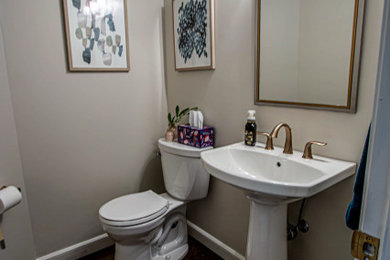 クリーブランドにある低価格の小さなトランジショナルスタイルのおしゃれなトイレ・洗面所 (分離型トイレ、ベージュの壁、無垢フローリング、ペデスタルシンク、茶色い床) の写真