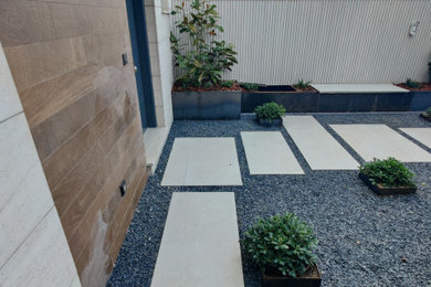 Modelo de jardín minimalista de tamaño medio en verano en patio delantero con exposición parcial al sol, adoquines de piedra natural y con madera