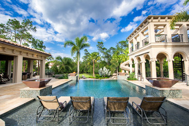 Expansive mediterranean courtyard rectangular infinity pool in Orlando with a water feature and tile.