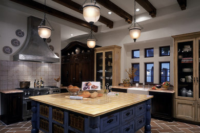 This is an example of an expansive eclectic u-shaped eat-in kitchen in Houston with a farmhouse sink, beaded inset cabinets, distressed cabinets, tile benchtops, stainless steel appliances, terra-cotta floors and with island.