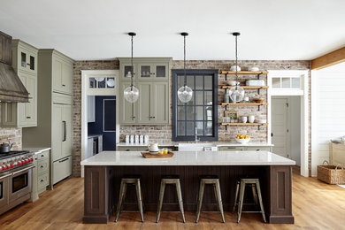 Open concept kitchen - large cottage light wood floor and beige floor open concept kitchen idea in Philadelphia with a farmhouse sink, shaker cabinets, quartz countertops, red backsplash, brick backsplash, paneled appliances, an island, green cabinets and white countertops