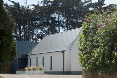 Ejemplo de fachada de casa blanca y gris de tamaño medio de dos plantas con revestimiento de metal, tejado a dos aguas y tejado de metal