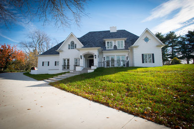 Inspiration for a large timeless white two-story stucco house exterior remodel in Other with a clipped gable roof