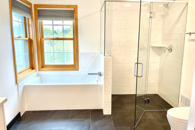 Diseño de cuarto de baño principal, doble y a medida tradicional grande con bañera empotrada, suelo de baldosas de porcelana, encimera de cuarcita y suelo negro