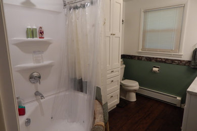 Inspiration for a mid-sized timeless master dark wood floor and brown floor bathroom remodel in Other with recessed-panel cabinets, white cabinets, a one-piece toilet, green walls, an integrated sink, granite countertops and gray countertops