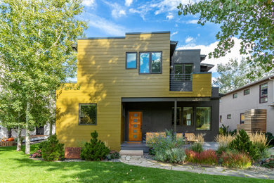 Exemple d'une façade de maison jaune tendance en panneau de béton fibré à un étage.