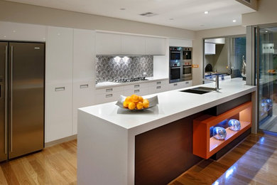 Inspiration for a mid-sized modern u-shaped open plan kitchen in Perth with a double-bowl sink, flat-panel cabinets, white cabinets, solid surface benchtops, grey splashback, ceramic splashback, stainless steel appliances, medium hardwood floors and with island.