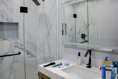 Example of a white tile and ceramic tile porcelain tile, white floor and single-sink bathroom design in Toronto with shaker cabinets, white cabinets, white walls, quartz countertops, a hinged shower door, white countertops and a niche