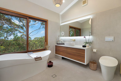 Large contemporary bathroom in Sydney with medium wood cabinets, a freestanding tub, a bidet, porcelain tile, porcelain floors, a vessel sink, solid surface benchtops, white benchtops, a single vanity and a floating vanity.