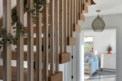 Imagen de escalera recta actual de tamaño medio con escalones de madera, contrahuellas de madera y barandilla de madera