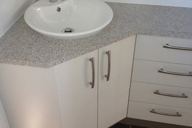 Photo of a small modern bathroom in Brisbane with white cabinets and laminate benchtops.