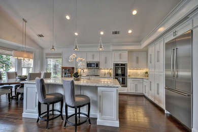 Eat-in kitchen - large transitional l-shaped dark wood floor eat-in kitchen idea in Sacramento with a single-bowl sink, recessed-panel cabinets, white cabinets, granite countertops, beige backsplash, stainless steel appliances and an island