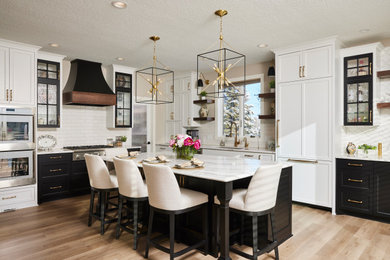 Large trendy l-shaped laminate floor and brown floor kitchen pantry photo in Minneapolis with an undermount sink, flat-panel cabinets, white cabinets, quartz countertops, white backsplash, ceramic backsplash, stainless steel appliances, an island and white countertops
