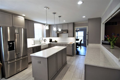 This is an example of a large transitional u-shaped eat-in kitchen in Other with a farmhouse sink, recessed-panel cabinets, grey cabinets, granite benchtops, white splashback, subway tile splashback, stainless steel appliances, porcelain floors, with island, beige floor and beige benchtop.