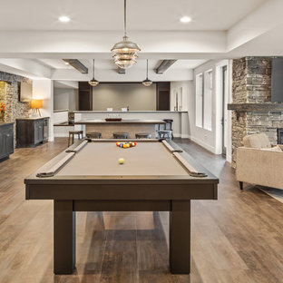 シンシナティの大きいカントリー風おしゃれな地下室 (半地下 (ドアあり)、白い壁、クッションフロア、標準型暖炉、石材の暖炉まわり、茶色い床) の写真