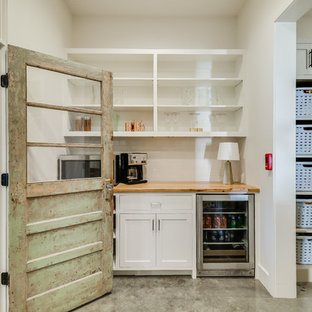 Large farmhouse kitchen pantry appliance - Example of a large country u-shaped concrete floor and gray floor kitchen pantry design in Jackson with a farmhouse sink, open cabinets, white cabinets, wood countertops, white backsplash, subway tile backsplash, stainless steel appliances and an island